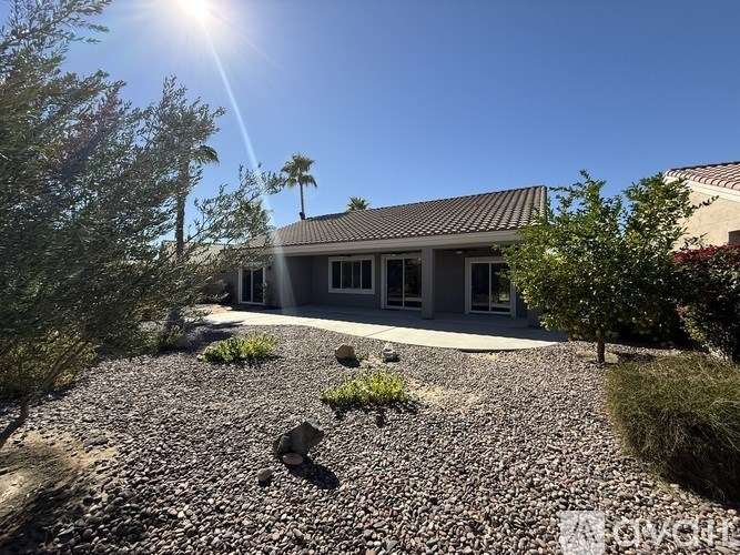 A sunny day with a clear blue sky and a patio with chairs and a table.