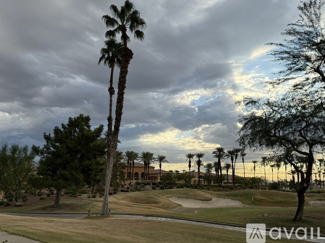 A golf course with palm trees and a cloudy sky.