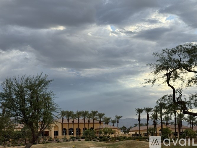 A cloudy sky over a residential area with palm trees.