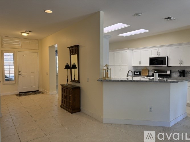 A kitchen with white cabinets and a large island with a sink.