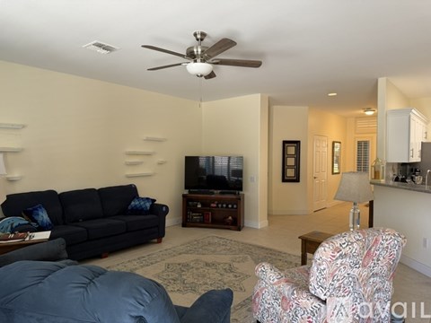 A living room with a black couch and a ceiling fan.