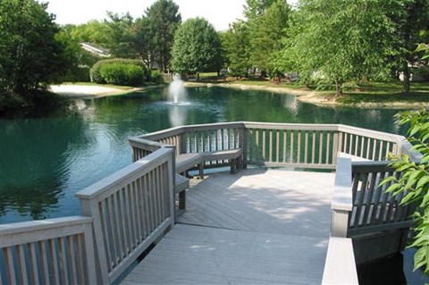 a wooden deck overlooking a pond with a fountain