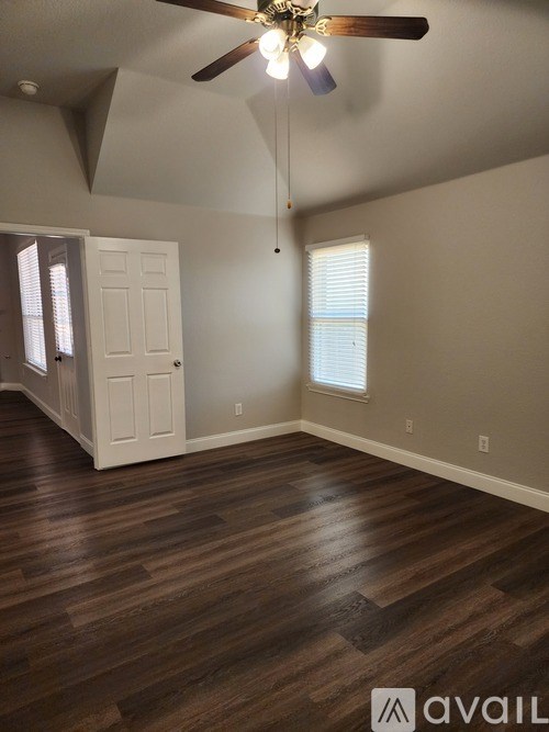 A room with a ceiling fan and wooden flooring.