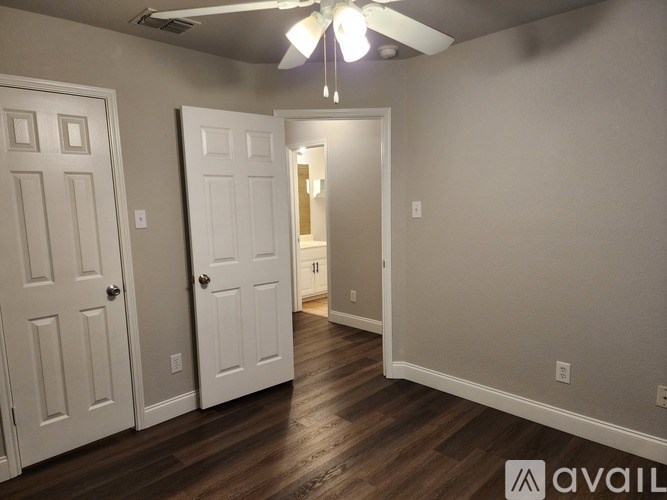 A room with a ceiling fan and two doors.