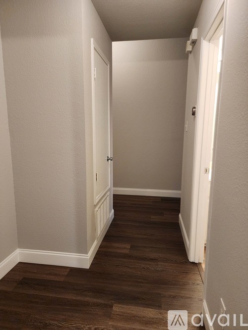 A hallway with wood flooring and white walls.