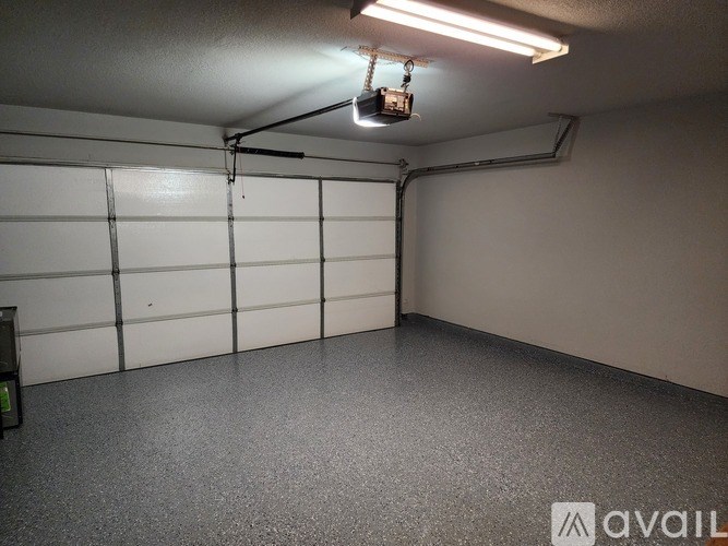 A garage with a white wall and a grey floor.