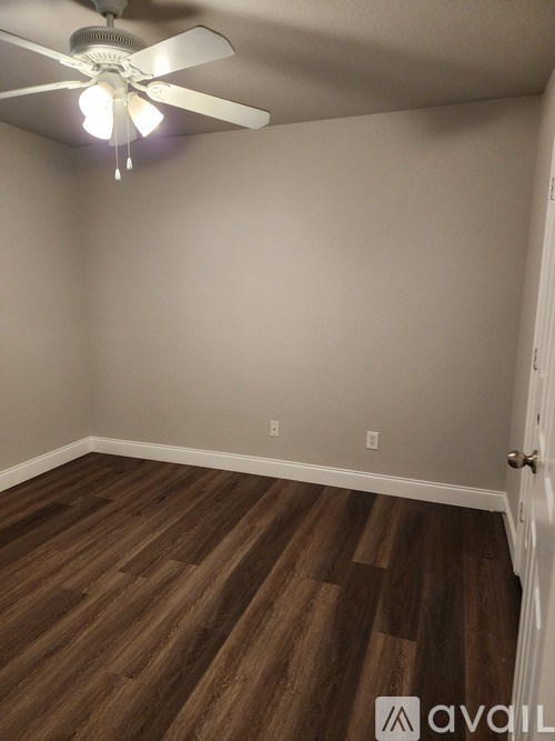 A room with a ceiling fan and wooden flooring.