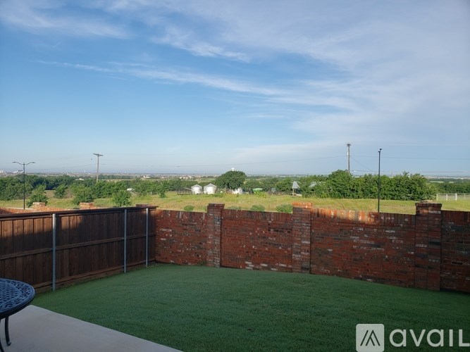 A backyard with a brick wall and a green lawn.