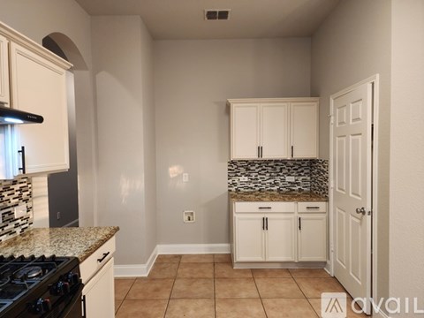 A kitchen with white cabinets and a black stove top oven.