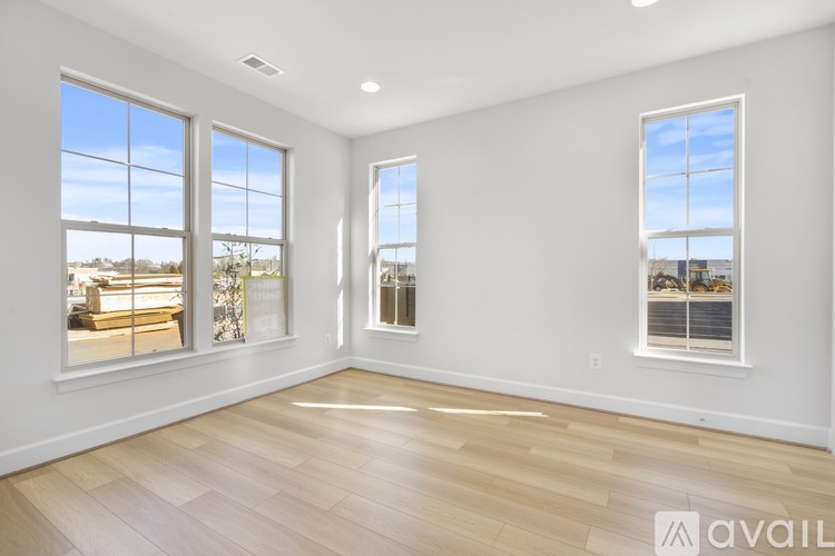 A spacious room with wooden floors and three windows.