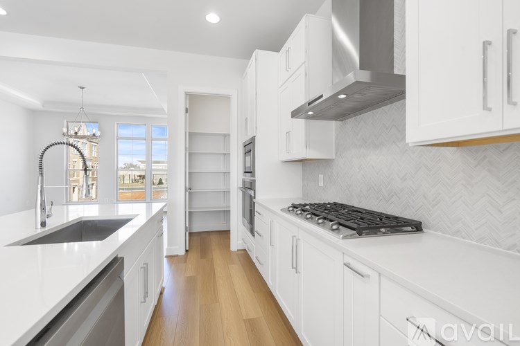 A modern kitchen with white cabinets and a black stove top.