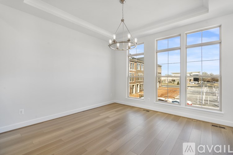 A room with a wooden floor and a large window overlooking a parking lot.