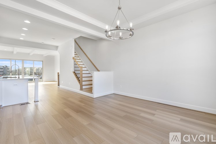 A spacious room with wooden flooring and a staircase.