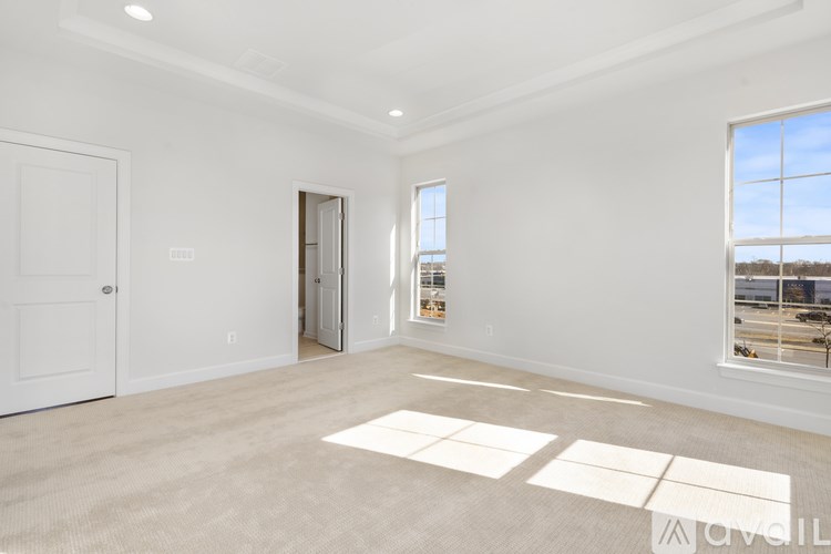 A spacious, empty room with a large window and a door leading to another room.