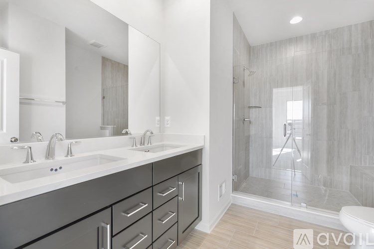A modern bathroom with a walk-in shower and double sinks.