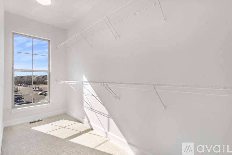 A white room with a window and a view of a parking lot outside.