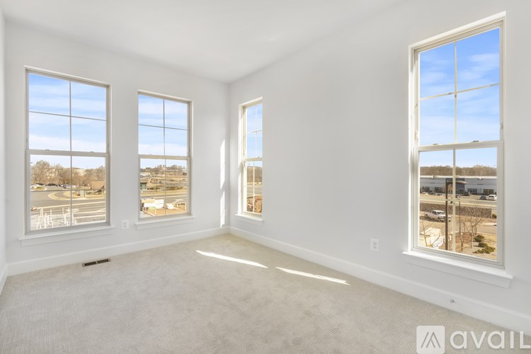 A spacious room with three windows overlooking a landscape.