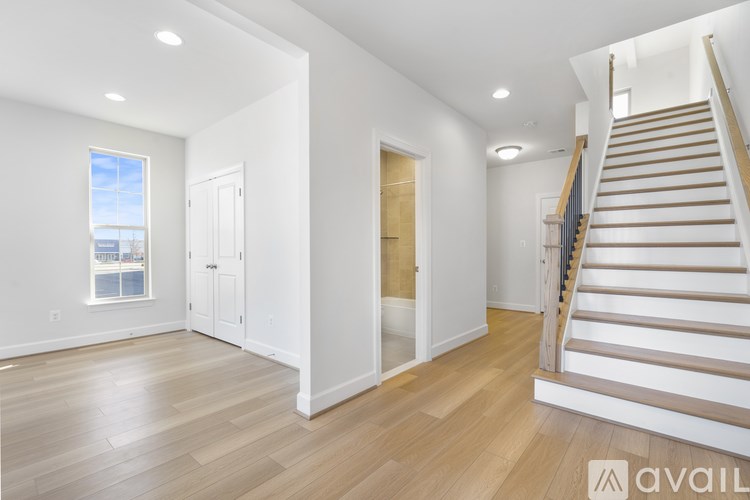 A spacious room with wooden floors and a staircase leading to another level.