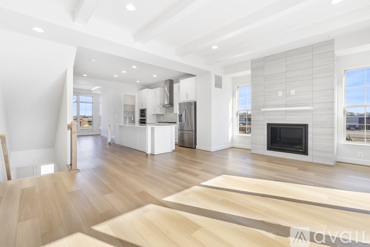 A modern living room with a fireplace and a kitchen in the background.