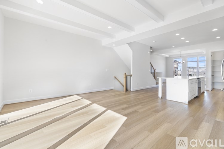 A spacious room with wooden flooring and a staircase.