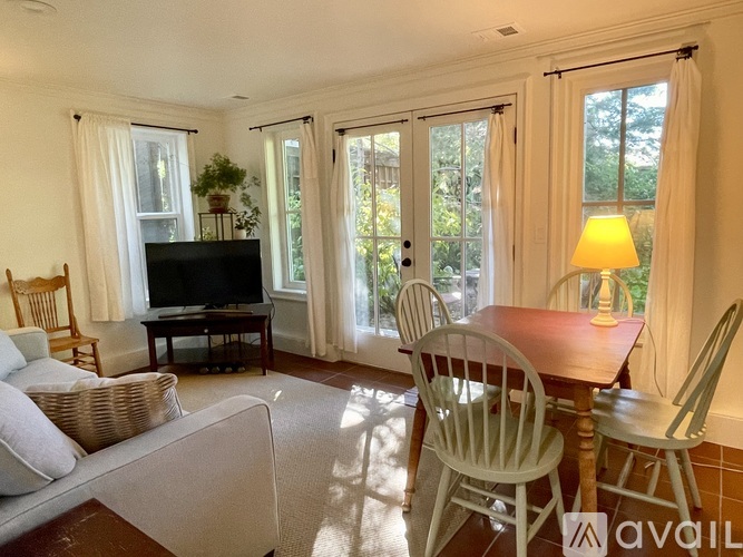 A living room with a television, a couch, a chair, a table, and a window.