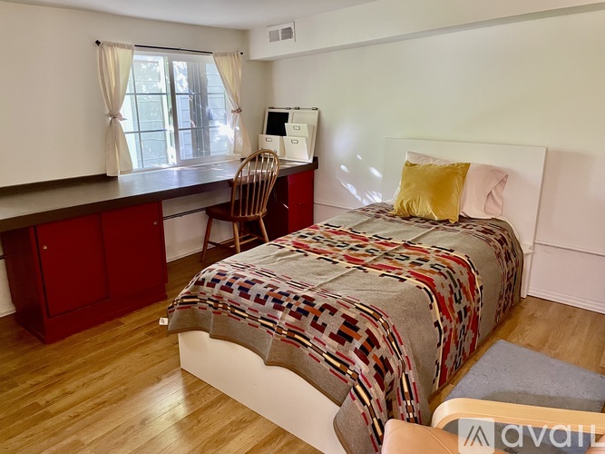 A bedroom with a bed, chair, and desk.