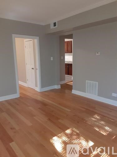 A room with wooden flooring and a doorway leading to another room.