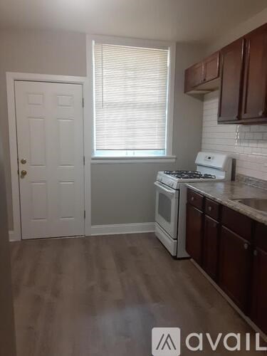 A kitchen with a white stove top oven and brown cabinets.