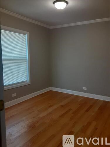 A room with wooden flooring and a window with blinds.