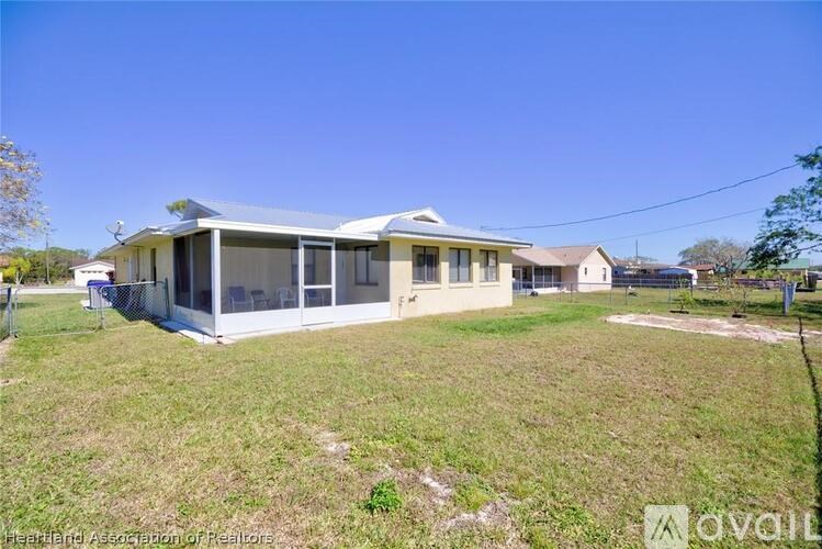 A house with a white exterior and a grey roof is surrounded by a grassy area.