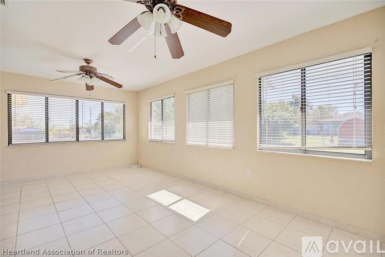 A room with a ceiling fan and three windows with blinds.