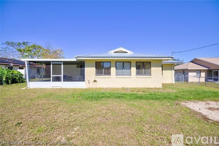 A house with a white fence and a green lawn in front.