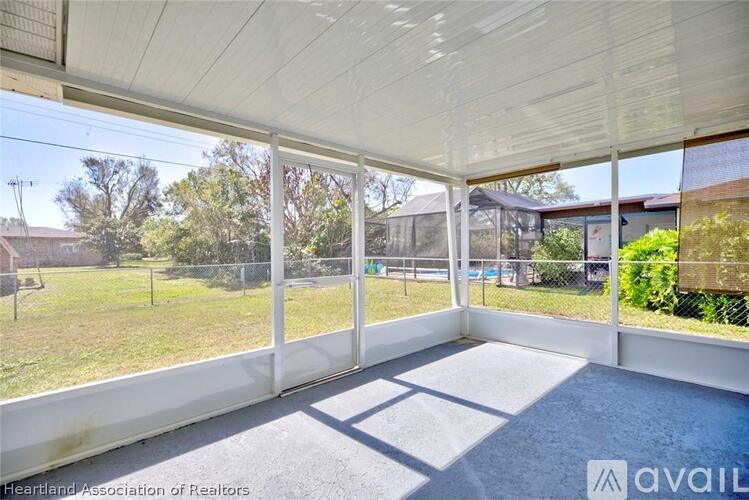 A sunny day in a spacious room with a view of a fenced yard and trees.