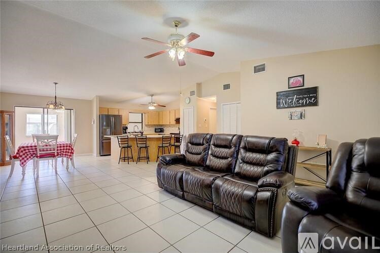 A living room with a black leather couch and a ceiling fan.