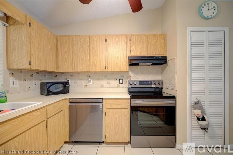 A kitchen with wooden cabinets and a clock on the wall.