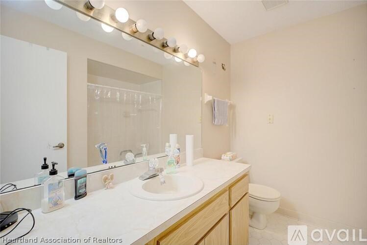 A bathroom with a white counter top and a mirror above it.