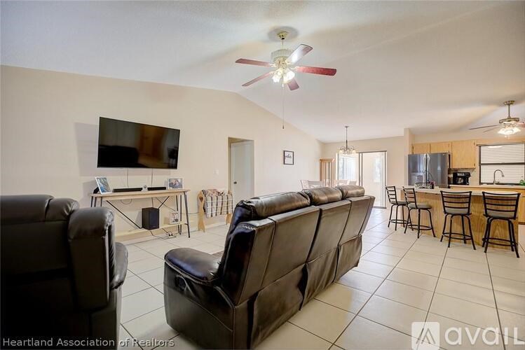A living room with a black leather couch and a television.