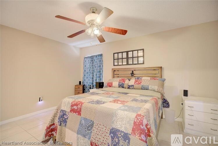 A bedroom with a bed, a ceiling fan, and a window with curtains.