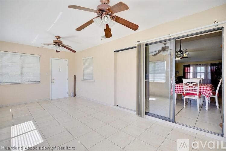 A room with a ceiling fan and sliding glass doors leading to a dining area.