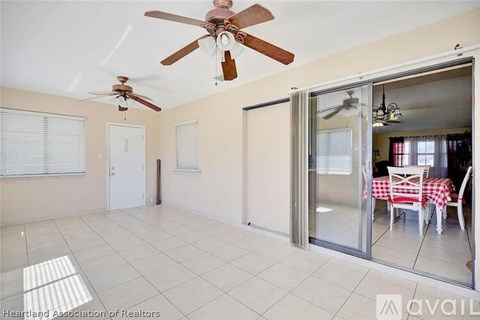 A room with a ceiling fan and sliding glass doors leading to a dining area.