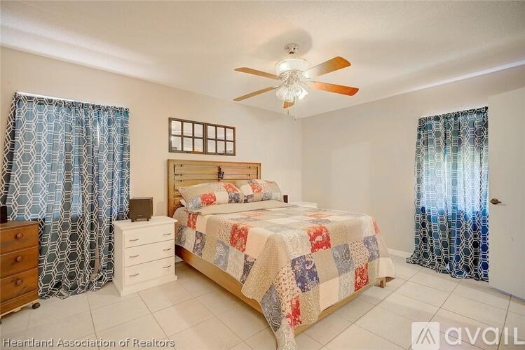 A bedroom with a bed, dresser, and window with curtains.