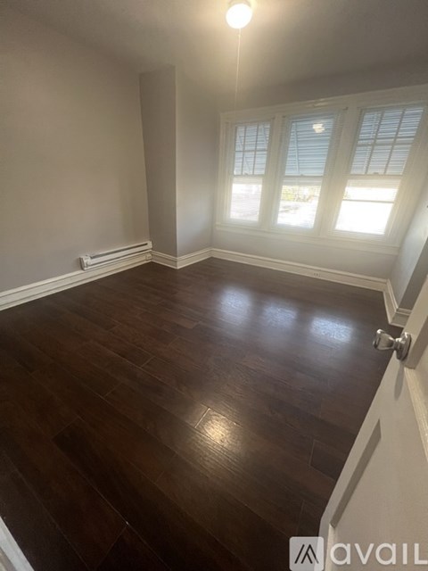 A room with wooden flooring and a window with blinds.