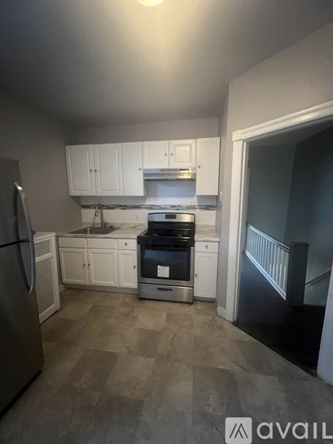 A kitchen with white cabinets and a stainless steel refrigerator.