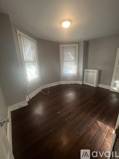 A room with wooden floors and two windows.