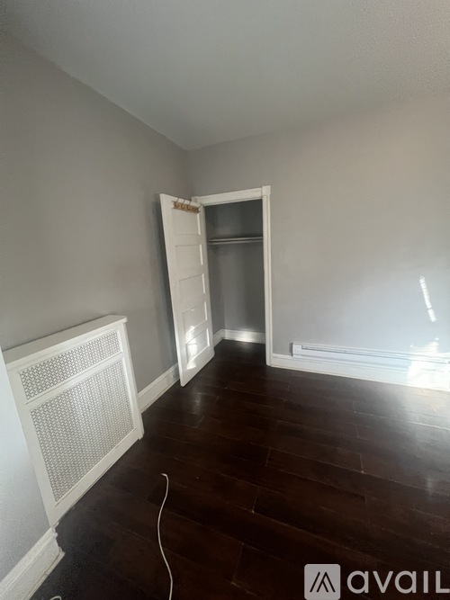A room with a white radiator and wooden flooring.