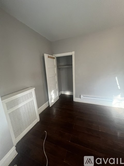 A room with a white radiator and wooden flooring.