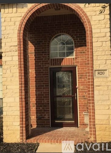A door with a glass window is set in a brick archway.