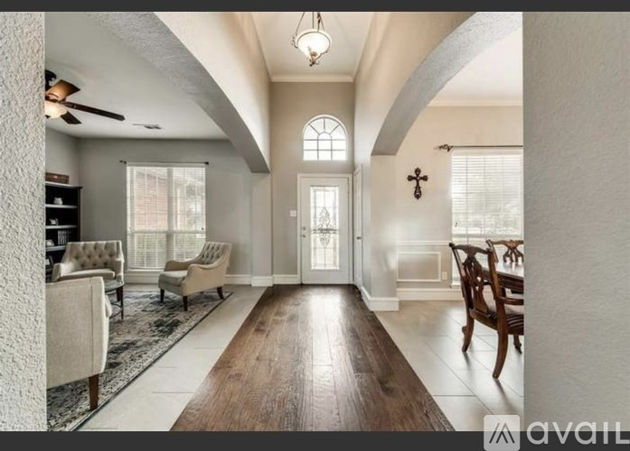 A spacious living room with a high ceiling and a large window.