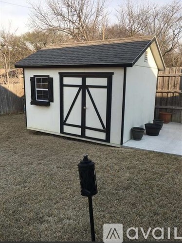 A small white shed with a black roof and black trim.