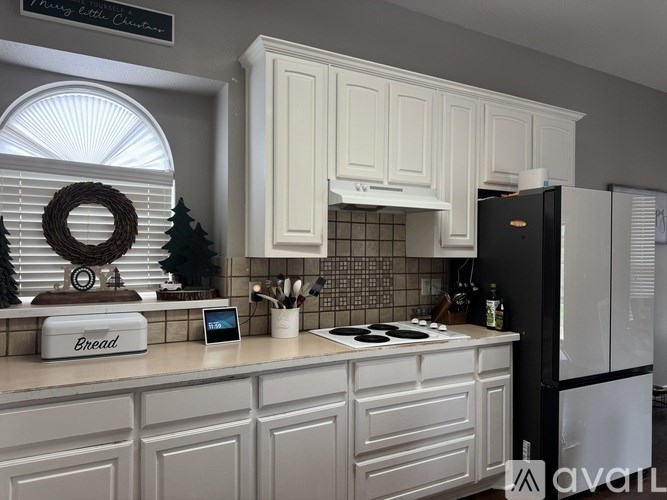 A kitchen with a black fridge and a white bread box.